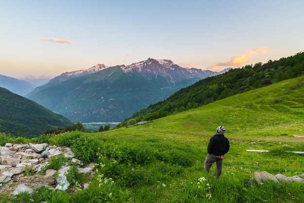 Eén persoon kijkt hoog in de alpen naar de zonsopgang