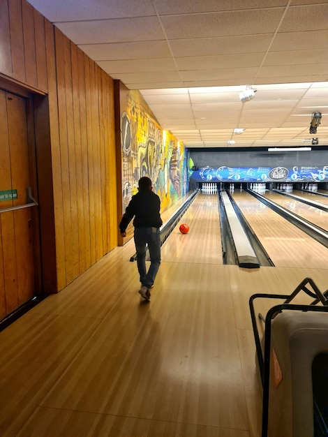 Een persoon loopt over een bowlingbaan met een bord waarop staat bowlen.