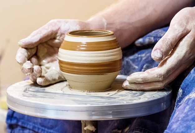 Een persoon maakt een pot op een tafel