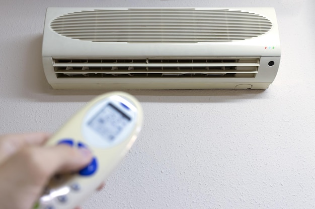 Een persoon met de afstandsbediening zet de airconditioner aan copia