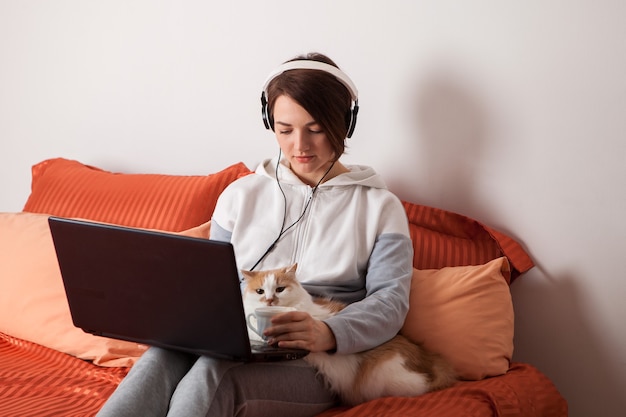 Een persoon met een kat en een laptop. een thuisscholing en thuiswerk