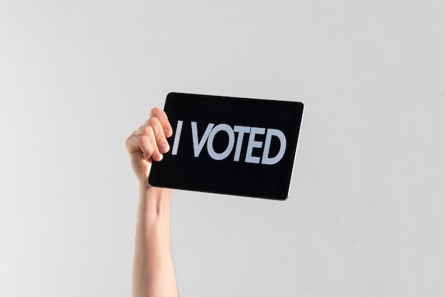 Een persoon met een opgeheven hand met zwarte plaat en tekst "ik heb gestemd", democratieverkiezing