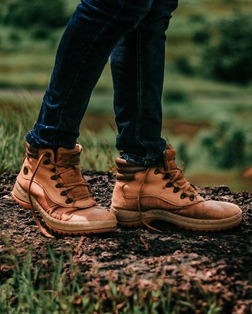 Foto een persoon met een paar bruine laarzen staat op een rotsachtige grond.