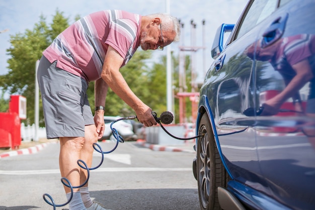 Een persoon pompt de banden van autowielen op met een compressor met manometer