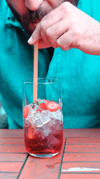 een persoon schenkt een drankje met aardbeien en rietjes