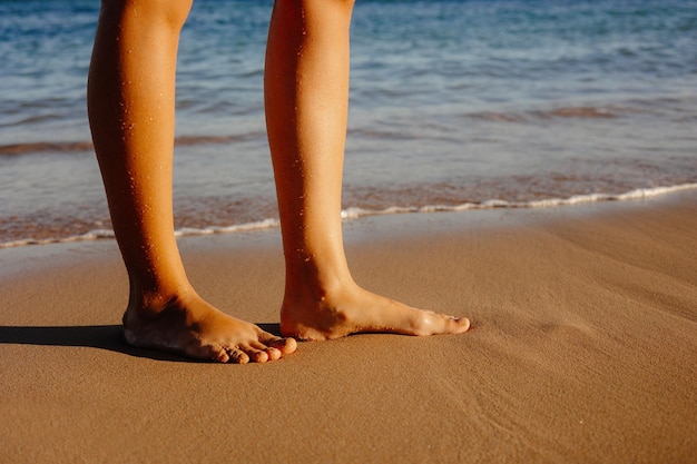 Een persoon staat op het strand voor de oceaan.