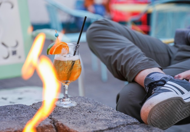 Een persoon zit op een vuurplaats met een glas jus d'orange voor zich.