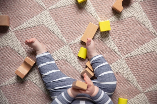 Foto een peuter die met houten speelblokken speelt in de kinderkamer, van bovenaf gefotografeerd