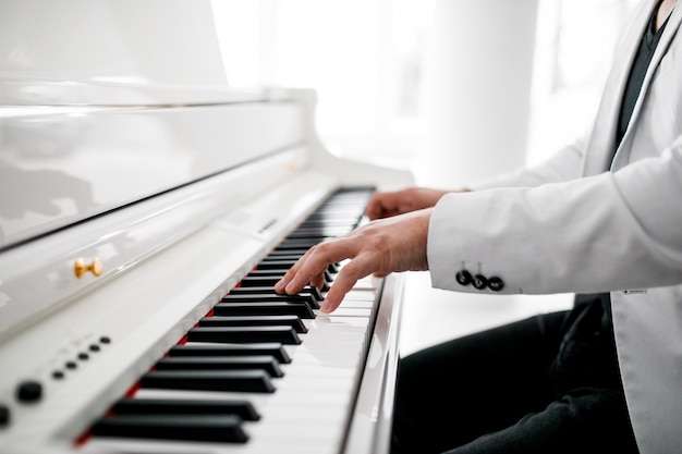 Een pianist in een wit pak speelt piano