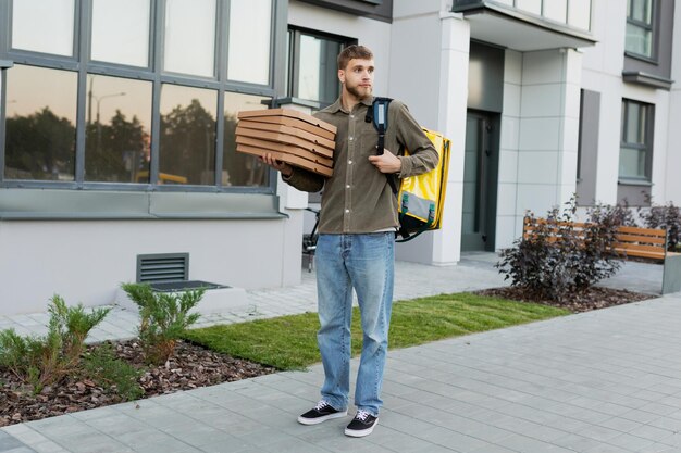 Een pizzabezorger staat in de buurt van het huis van de klant Snelle bezorging van een restaurant tijdens een pandemie