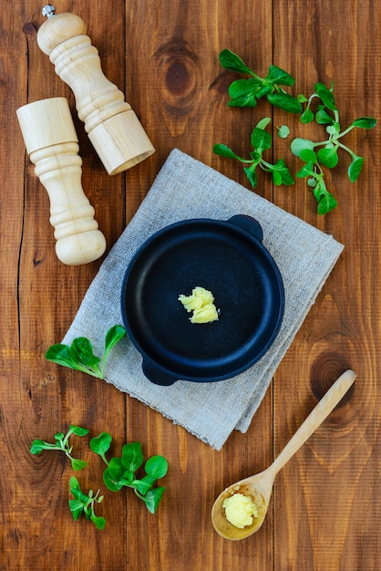 Een plakje ghee boter in een gietijzeren pan met greens en kruiden.