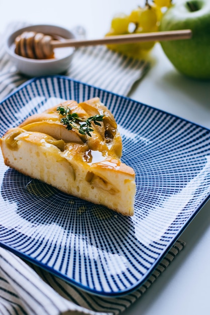 Een plakje verse appeltaart met druiven en honing op een blauwe plaat. Ontbijt.