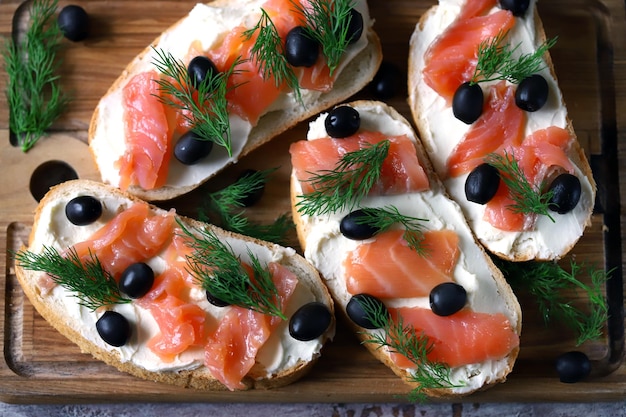 Een plankje brood met gerookte zalm en zwarte olijven.