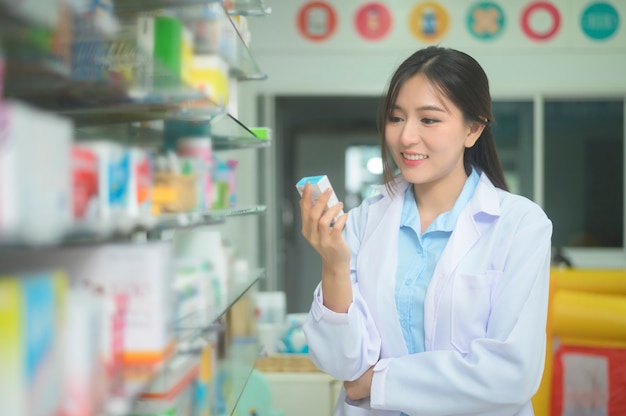 Een portret van aziatische vrouwenapotheker die laboratoriumlaag dragen in een moderne apotheekdrogisterij