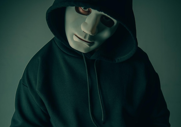 Een portret van een anonieme hacker met een masker en een zwarte hoodie die met zijn hoofd schuin zit en angstaanjagend Hacking- en malwareconcept