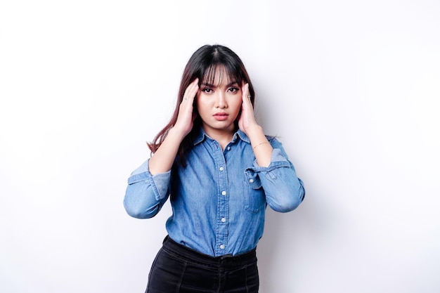 Een portret van een Aziatische vrouw, gekleed in een blauw shirt geïsoleerd door een witte achtergrond, ziet er depressief uit