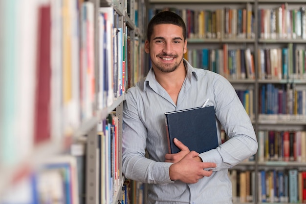 Een portret van een blanke studente man in bibliotheek ondiepe scherptediepte