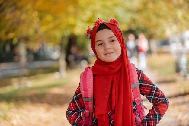 Een portret van een gelukkig moslimstudentenmeisje in mode-hijab met schoolrugzak in het herfstpark.