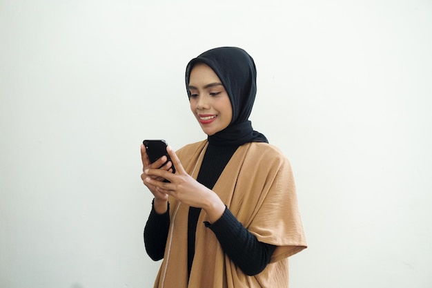 Een portret van een gelukkige Aziatische moslimvrouw die een telefoon met een hoofddoek draagt