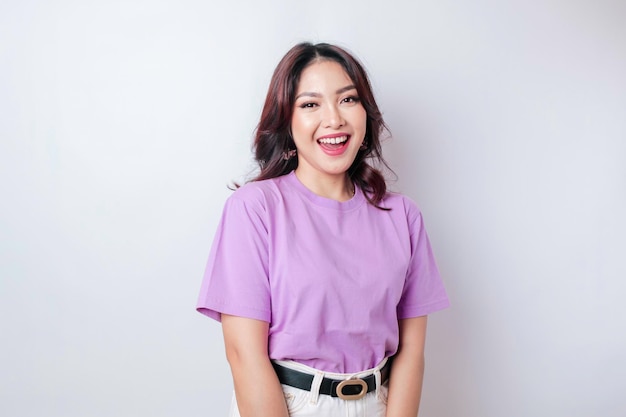 Een portret van een gelukkige Aziatische vrouw die een lila paarse t-shirt draagt, geïsoleerd door een witte achtergrond