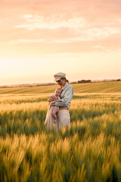 Een portret van een jonge moeder met een baby in haar armen bij zonsondergang in het veld happy family concept