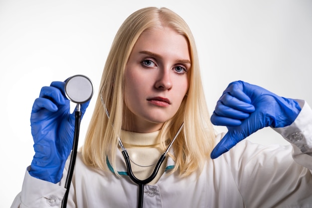 Een portret van een jonge vrouwelijke stagiaire met een stethoscoop in haar rechterhand en naar beneden gericht