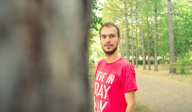 Een portret van een knappe man met baard tegen de achtergrond van groene bomen in het park