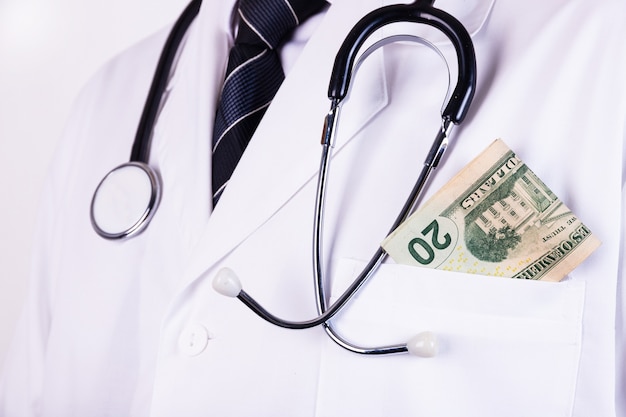 Een portret van een mannelijke arts met geld in zijn zak op wit wordt geïsoleerd