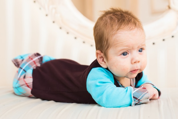 Een portret van een schattige pasgeboren baby in een wit als een hoed die op zijn buik ligt en lacht