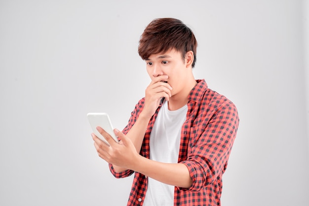 Een portret van een verraste jonge man met mobiele telefoon