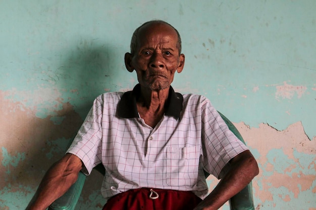 Een portret van Indonesische oude opa zittend in de stoel