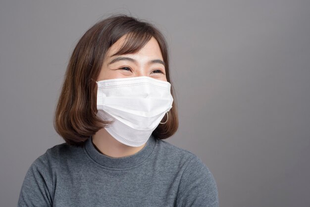 Foto een portret van jonge mooie aziatische vrouw die een chirurgisch masker draagt, covid19 pandemie en luchtvervuiling (pm2