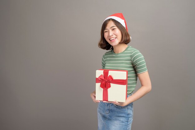 Een portret van mooie vrouw die de rode doos van de de holdingsgift van de Kerstmanhoed over studio draagt