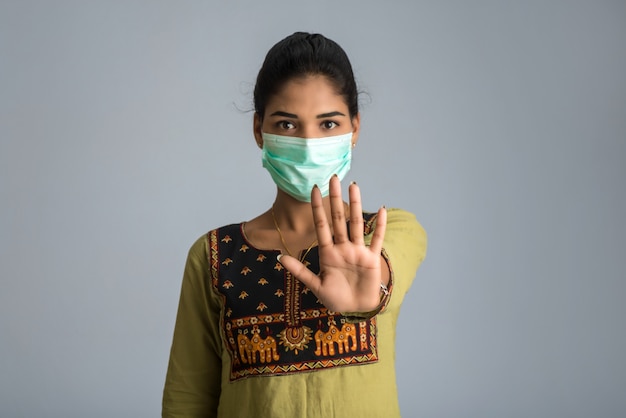 Een portret van vrouw met medisch gezichtsmasker dat eindeteken met handen toont. Gezondheidszorg en geneeskunde concept