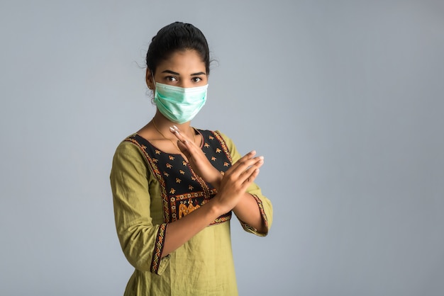 Een portret van vrouw met medisch gezichtsmasker dat eindeteken met handen toont. Gezondheidszorg en geneeskunde concept