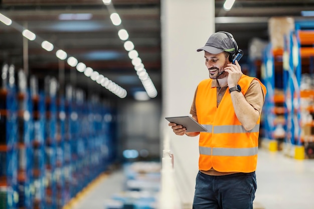 Een post-expres supervisor die een headset voor voicepicking gebruikt en naar de tablet lacht