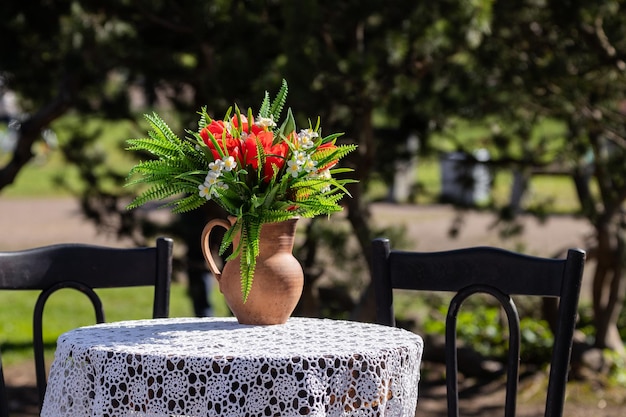 Een pot met een boeket bloemen op een tafel met een tafelkleed buiten