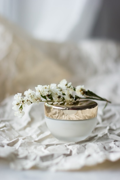 Een potje crème close-up. gezichtscrème met witte bloemen op een pot. Gezichtscrème in glazen pot met gouden deksel