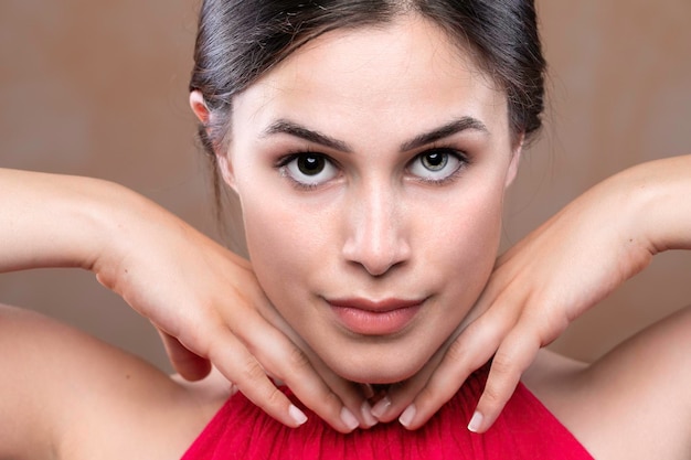 Een prachtig brunette meisje toont zelfvertrouwen in uiterlijk terwijl ze poseert met handen onder de kin