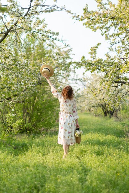 Een prachtig meisje loopt in een bloeiende lentetuin. Het concept van eenheid van de mens met de natuur