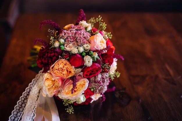 Een prachtig rood bruidsboeket ligt op een houten tafelMix van vetplanten, orchideeën en rozen