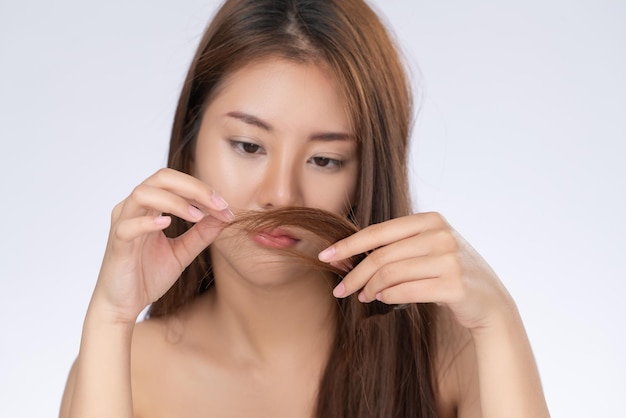 Een prachtige jonge vrouw voelt zich onzeker over haar beschadigde haar.