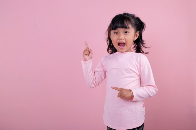 Een prachtige kinderen die iets wijzen met een zacht roze T-shirt