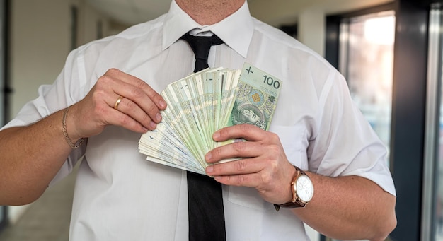 Een prachtige verfijnde man houdt Poolse zloty's in zijn sterke handen Het concept van een hoog inkomen