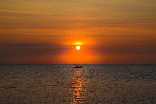 Foto een prachtige zonsondergang in de avond een vissersboot passeerde op bang saen beach, thailand.