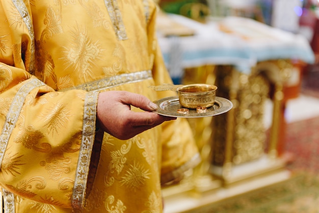 Een priester in de kerk met een dienblad met trouwringen