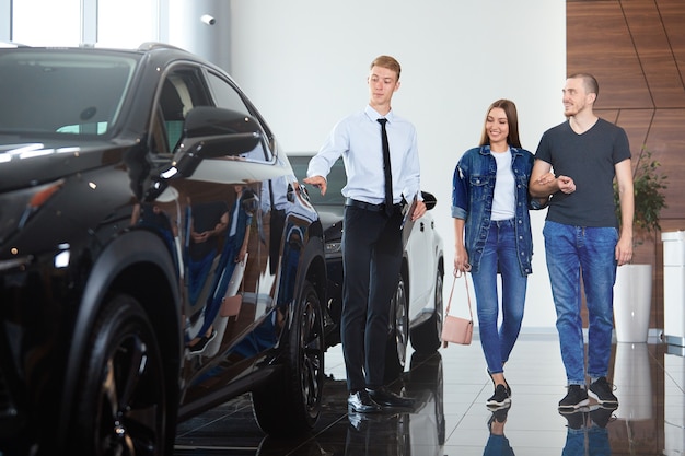 Een professionele autodealermanager die een auto laat zien aan klanten in een autodealer