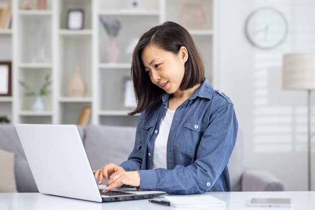Een professionele Aziatische vrouw is verdiept in werk aan een laptop zit in een goed verlichte en netjes gerangschikt