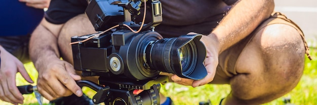 Een professionele cameraman bereidt een camera en een statief voor voordat hij gaat fotograferen BANNER, lang formaat