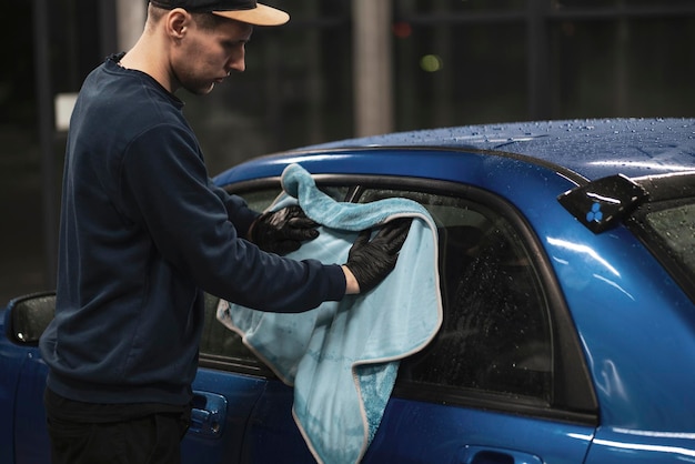 Een professionele detailer die het autooppervlak afveegt met een microvezeldoek in de werkplaats